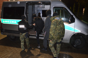 Funkcjonariusze Straży Granicznej prowadzą zatrzymanych cudzoziemców 