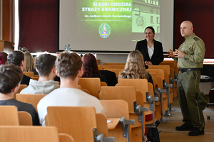 Sala wykładowa. Studenci siedzący na krzesłach. Przed nimi stoi st. chor. SG Mateusz Buchta, za nim wyświetlona jest prezentacja. Sala wykładowa. Studenci siedzący na krzesłach. Przed nimi stoi st. chor. SG Mateusz Buchta, za nim wyświetlona jest prezentacja.