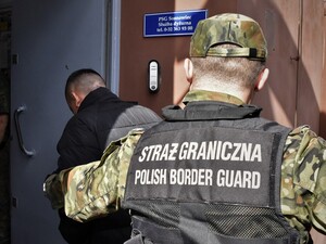 Funkcjonariusz SG prowadzi osobę zatrzymaną Funkcjonariusz SG prowadzi osobę zatrzymaną