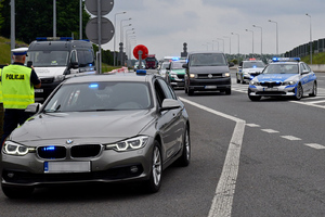  Zatrzymanie pojazdu na autostradzie przez Policje i Straż Graniczną. Na pierwszym planie z lewej nieoznakowany pojazd. Za nim zatrzymywany samochód a po jego stronach radiowozy Policji i Staży granicznej
