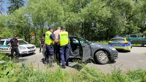  Dwóch funkcjonariuszy policji zakłada kajdany pasażerowi samochodu ściganego.