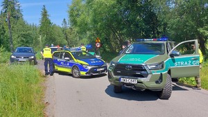 Samochód Straży Granicznej i Policji blokują drogę. Po lewej stoi zatrzymany pojazd.