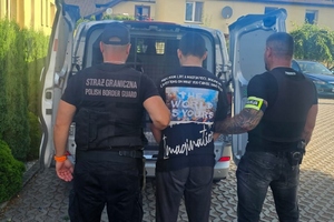  Funkcjonariusz Straży Granicznej i Policji prowadzą zatrzymanego do samochodu