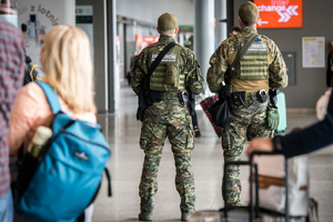Lotnisko w Katowicach. Funkcjonariusze Zespołu Interwencji Specjalnych stoją tyłem, obok nich znajdują się podróżni.