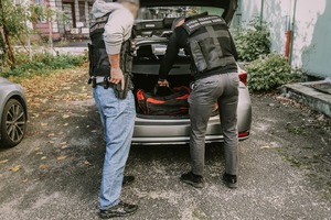 Dwóch funkcjonariuszy Straży Granicznej. Jeden wyciąga walizkę z bagażnika