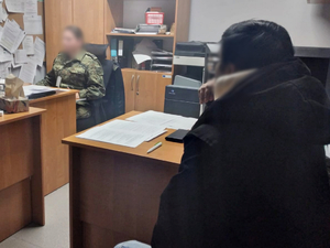  Funkcjonariusz Straży Granicznej siedzi przy komputerze a osoba zatrzymana przy biurku.