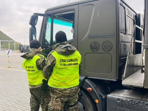  2 funkcjonariuszy stojących przy samochodzie