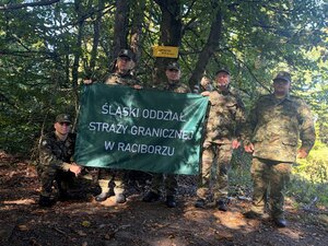 Funkcjonariusze trzymający flagę z napisem: Śląski Oddział Straży Granicznej w Raciborzu.