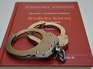  Zdjęcie ilustracyjne. Kodeks Karny a na nim położone kajdanki